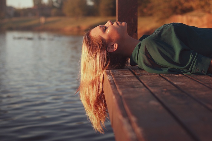 Woman lying on a pier by the water