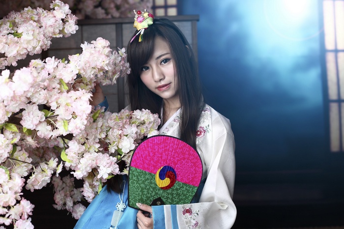 Asian woman in traditional Korean hanbok holding a fan