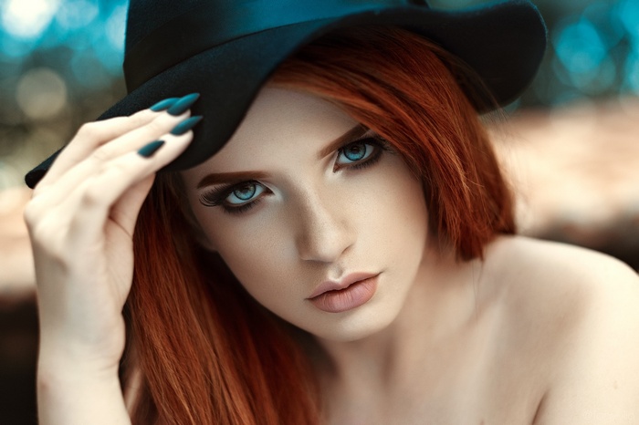 Woman with red hair and blue eyes wearing a black hat