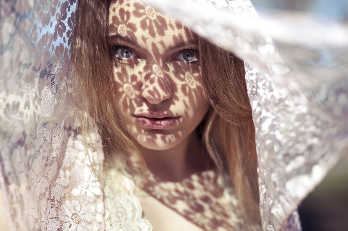 Woman with lace veil and dappled sunlight on face