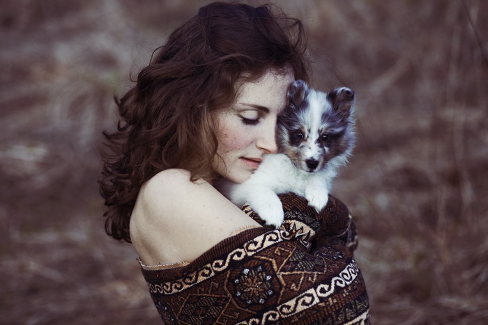 Woman holding a puppy wrapped in a blanket