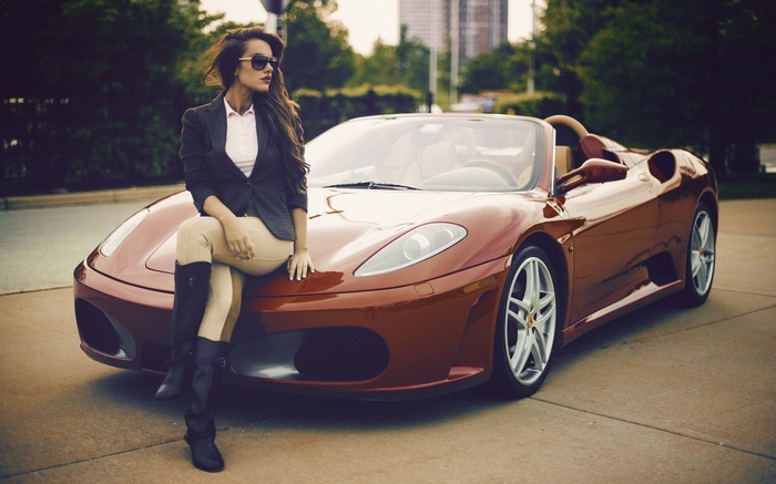 Woman in sunglasses sitting on a red Ferrari