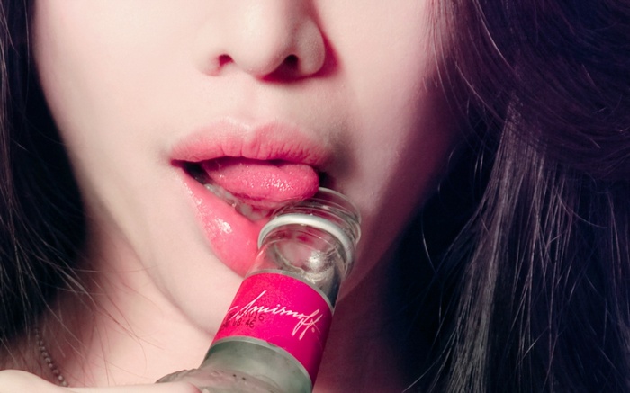 Woman licking a Smirnoff vodka bottle