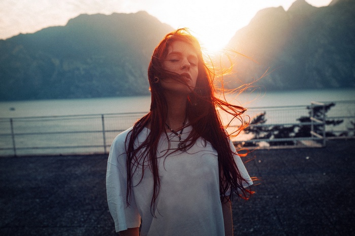 Woman with red hair in the wind at sunset