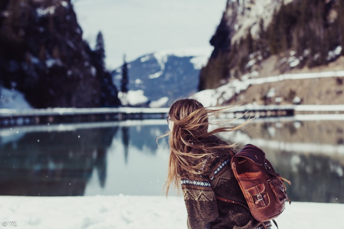 Woman with backpack by a lake in the snow
