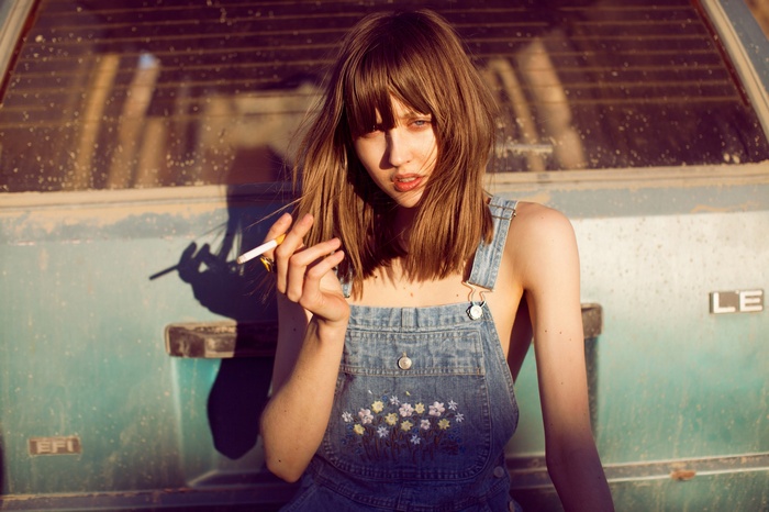 Woman in overalls smoking a cigarette