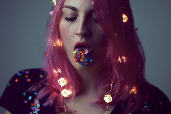 Woman with pink hair and confetti in mouth