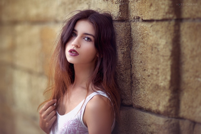 Woman with dyed hair leaning against a stone wall
