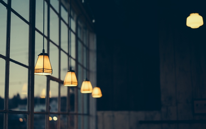 Four pendant lamps hanging in front of a large window