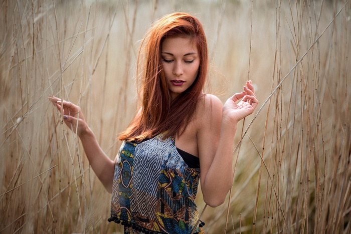 Redhead woman posing in tall dry grass