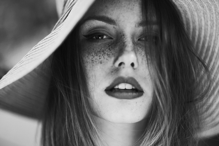 Monochrome portrait of a woman with freckles wearing a hat