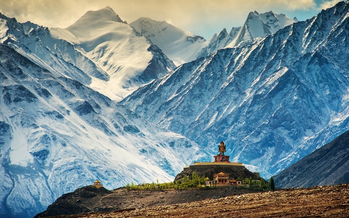 Buddha statue on a hill with snowy Himalayas