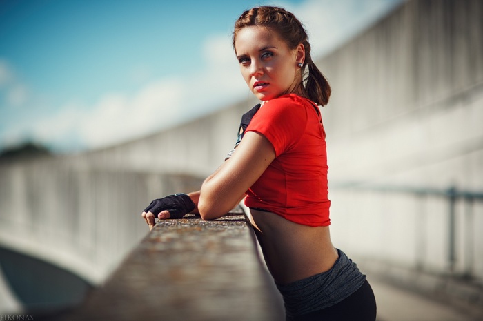 Woman in red T-shirt and gloves leaning on railing