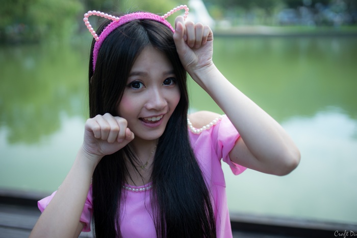 Young woman with cat ears headband and pink dress