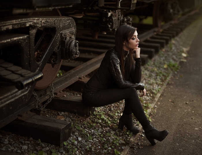 Woman in black clothing sitting on train tracks
