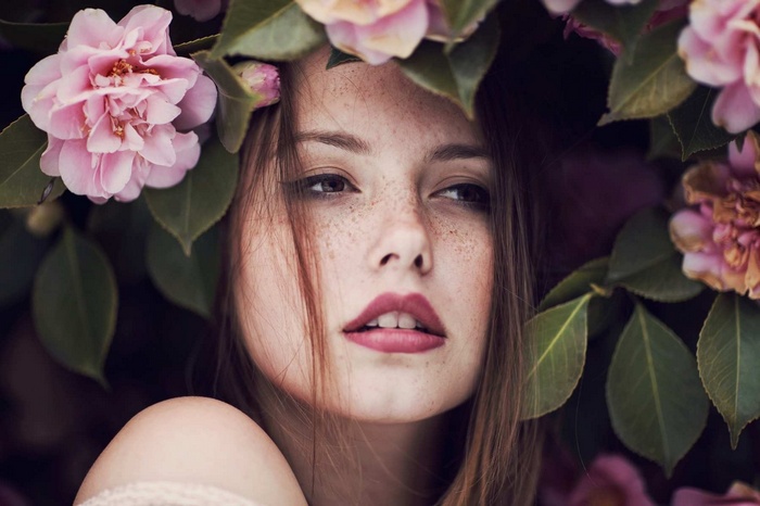 Woman with freckles surrounded by pink flowers