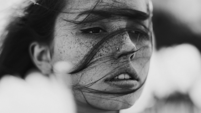 Monochrome portrait of a woman with freckles and hair in her face