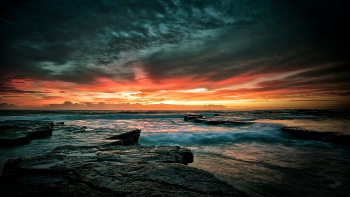 Ocean waves crash on rocky shore at sunset