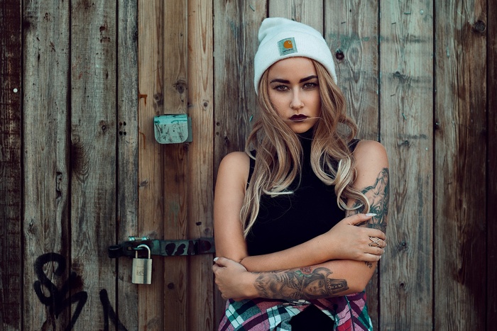 Woman with tattoos wearing a beanie and plaid shirt