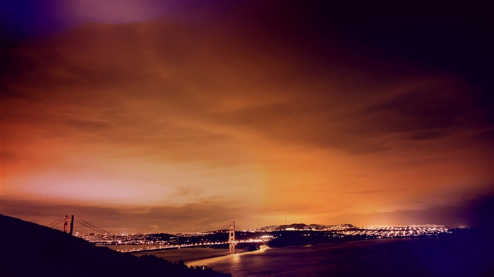 Golden Gate Bridge at night with city lights and clouds
