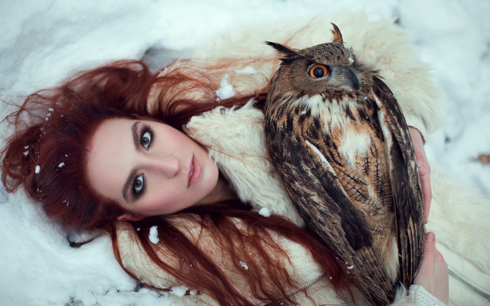 Woman with red hair and owl in the snow