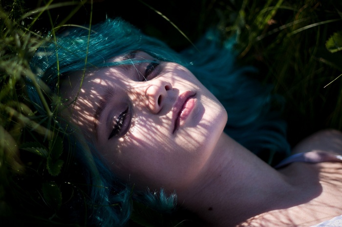 Woman with blue dyed hair lying in grass