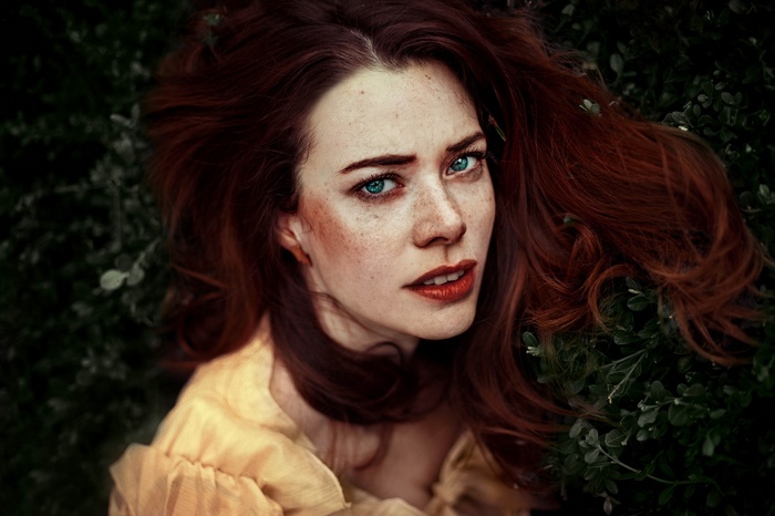 Woman with red hair and freckles looking at viewer