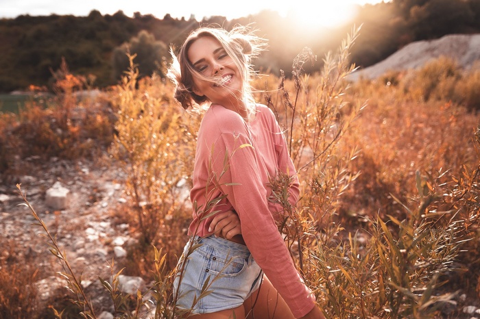 Woman smiling in a field at sunset