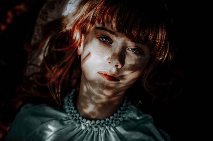Woman with red hair and blue eyes lying down