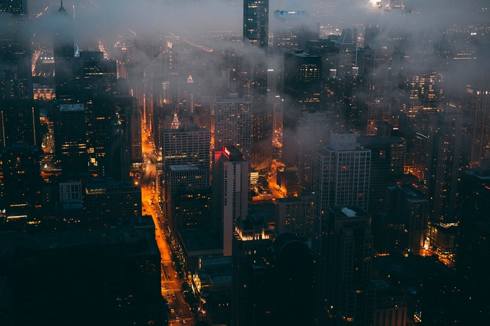 Misty city skyline at night with glowing streets