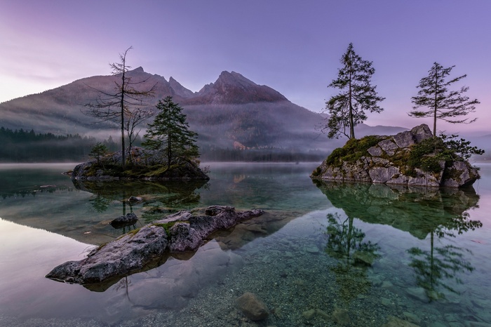 Islands with trees in a misty lake at sunrise