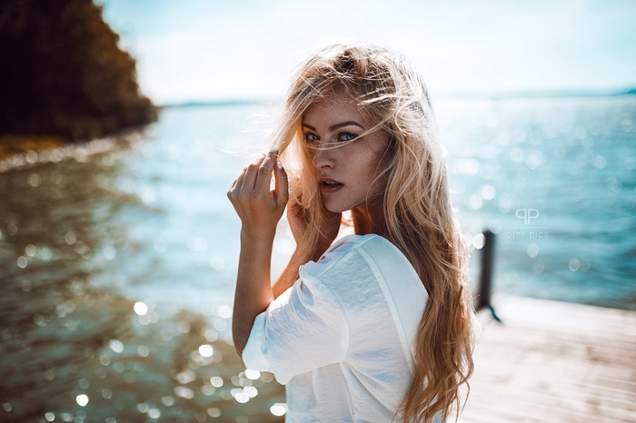 Woman with blonde hair on a pier by the water