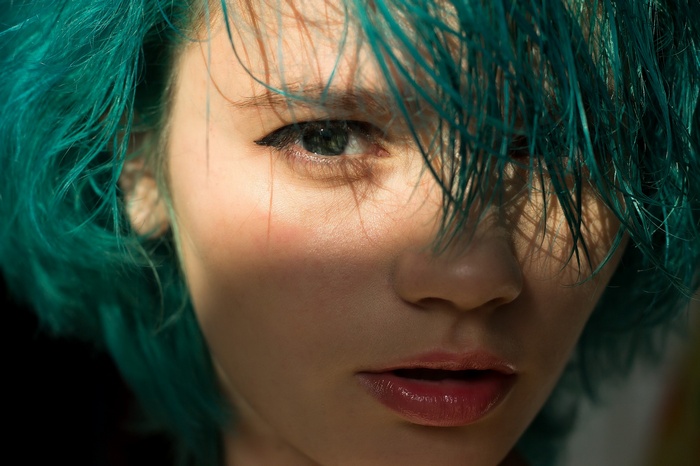 Woman with teal dyed wet hair and blue eyes