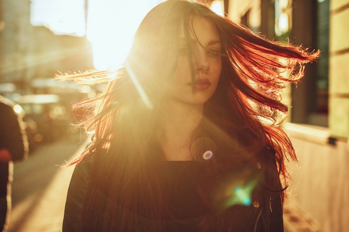 Woman with red hair in sunlight on a street