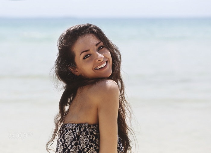 Woman smiling at the beach with the sea in the background