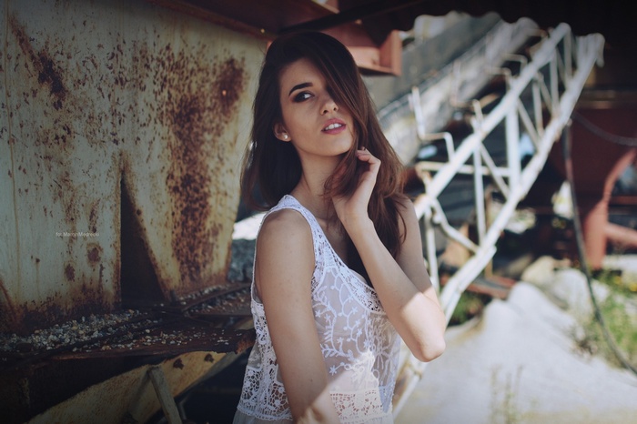 Brunette woman in white clothing in urban decay setting