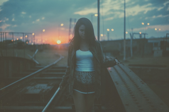 Woman walking on railway tracks at sunset