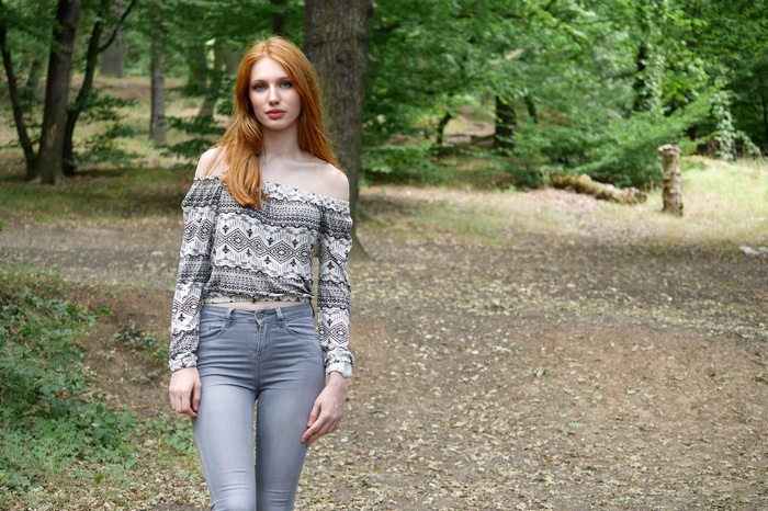 Redhead woman with bare shoulders in a forest