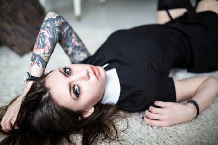 Anastasia Lomakova lying on the floor in a black dress