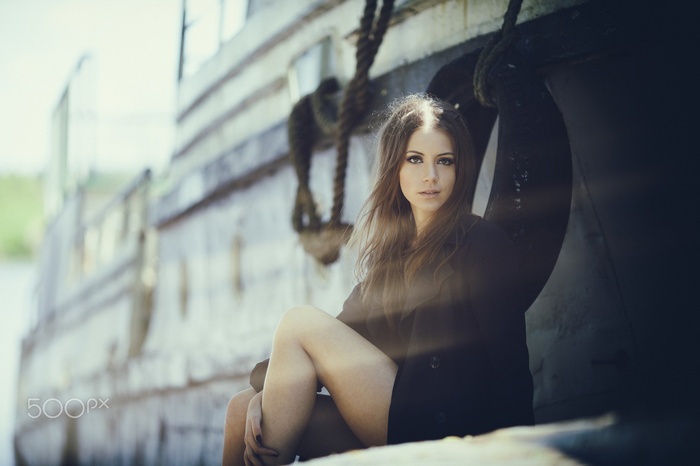 Model Ksenia Kokoreva sitting by a boat