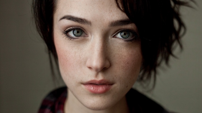 Woman with short dark hair and freckles looking at viewer