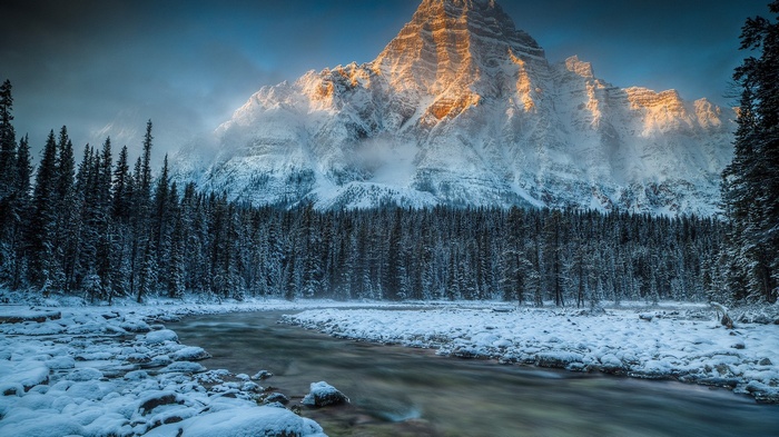 Snowy mountains and river in a winter forest