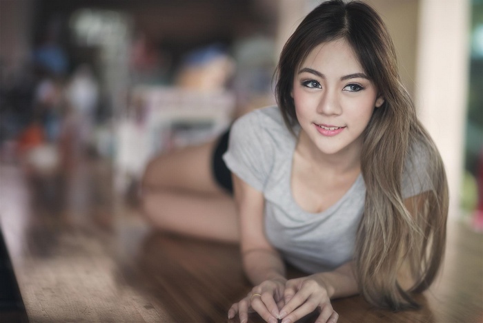 Young Thai woman lying on a wooden surface