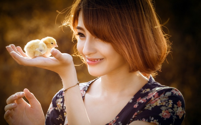 Asian woman holding two baby chicks