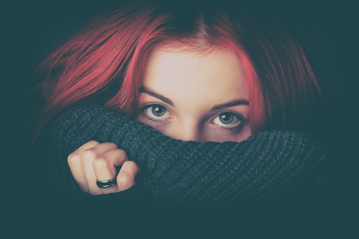 Woman with red hair hiding behind a scarf