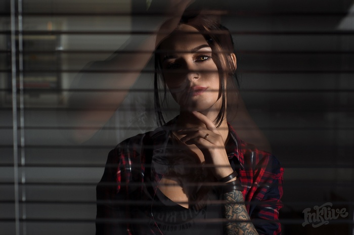 Anastasia Rozhdestvenskay behind blinds with tattoos