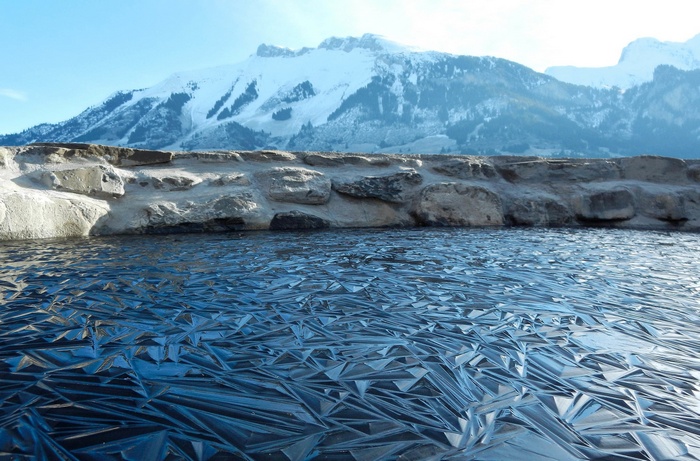 Frozen lake with stone wall and snowy mountains in Switzerland
