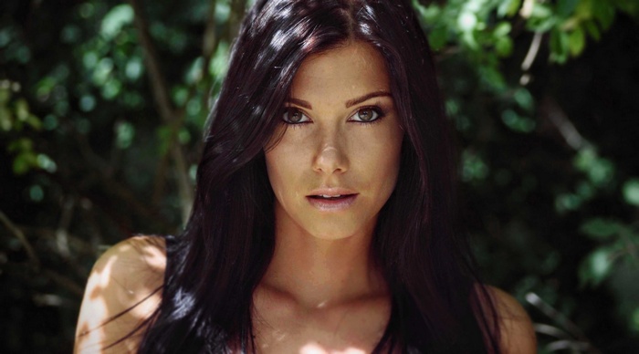 Woman with dark hair in dappled sunlight