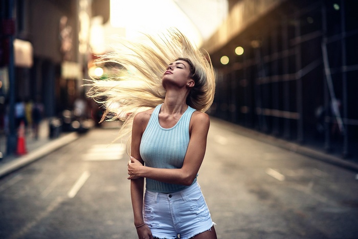 Woman with blonde hair flipping in a city street