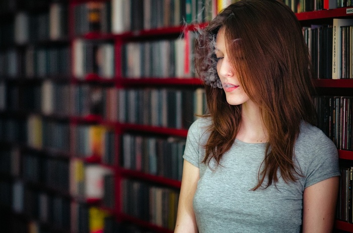 Woman smoking in front of bookshelves